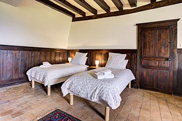 Chambre à lits séparés avec poutres apparentes au Château de Juvardeil