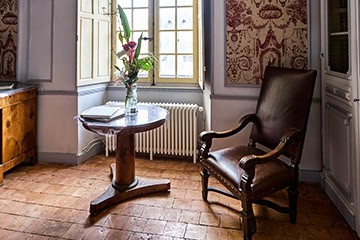 Coin lecture avec fauteuil ancien près d’une fenêtre au Château de Juvardeil en Anjou